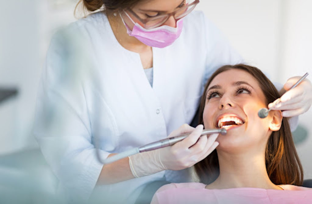 A dentist working on her smiling female patient