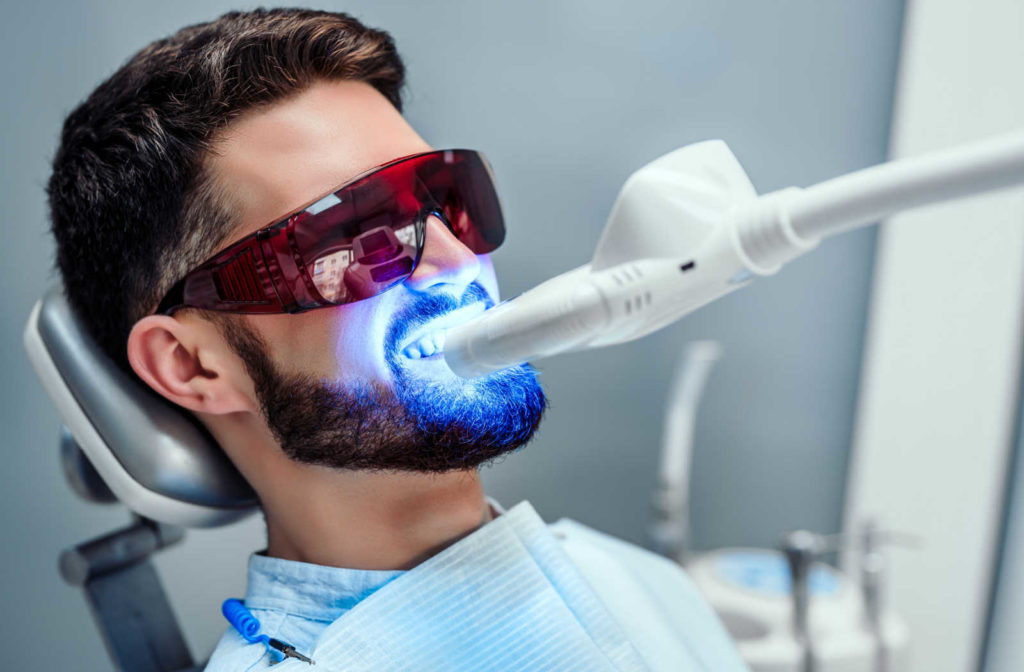 A man wearing protective eyewear while getting a teeth whitening treatment done at the dentist office.