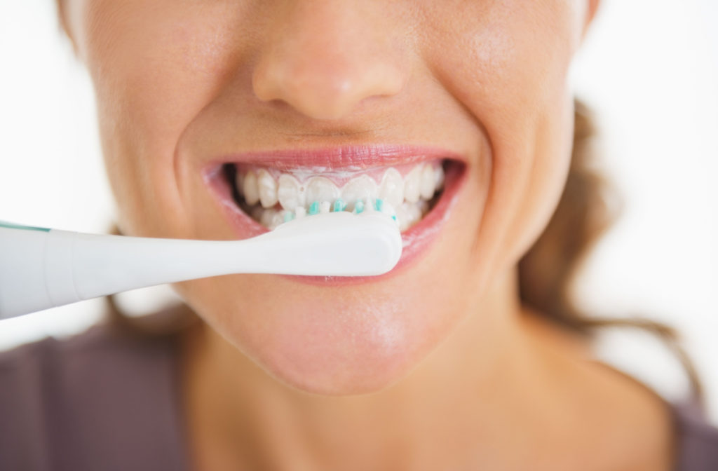A close up of a woman brushing her teeth.