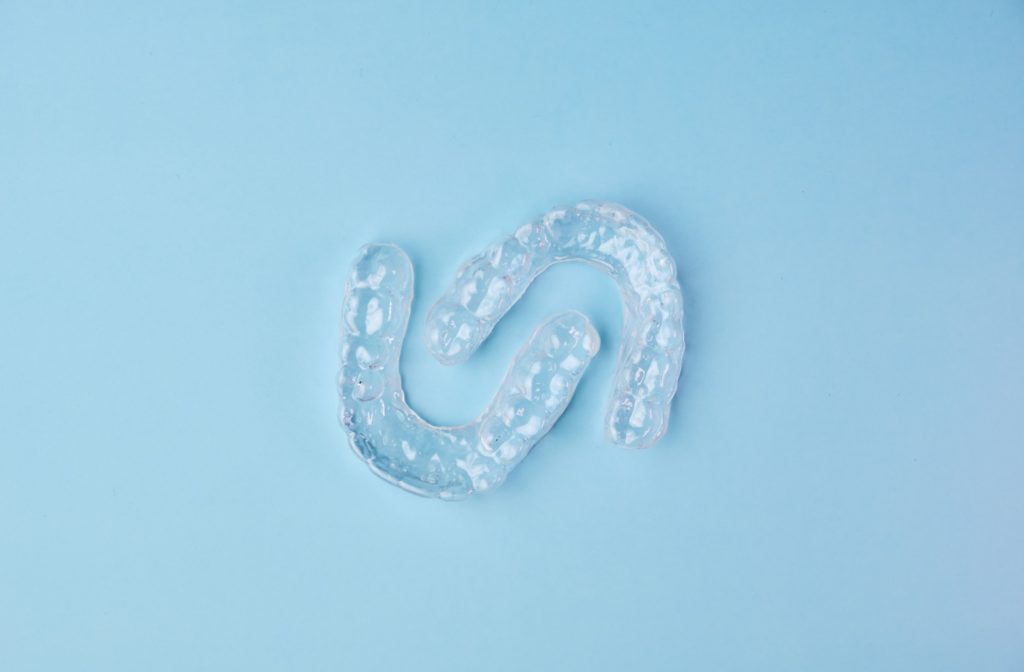 A photo of a set of Invisalign clear aligners, side by side, against a blue background.