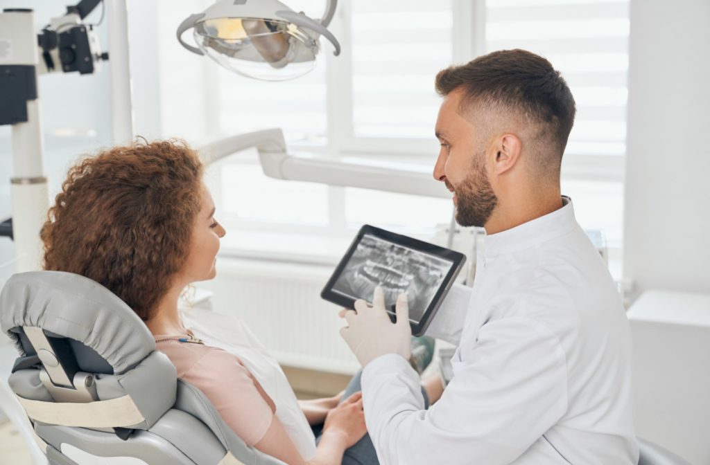 a dentist shows their patient an x-ray of the patient's bite to discuss the proper treatment plan for their bite misalignment