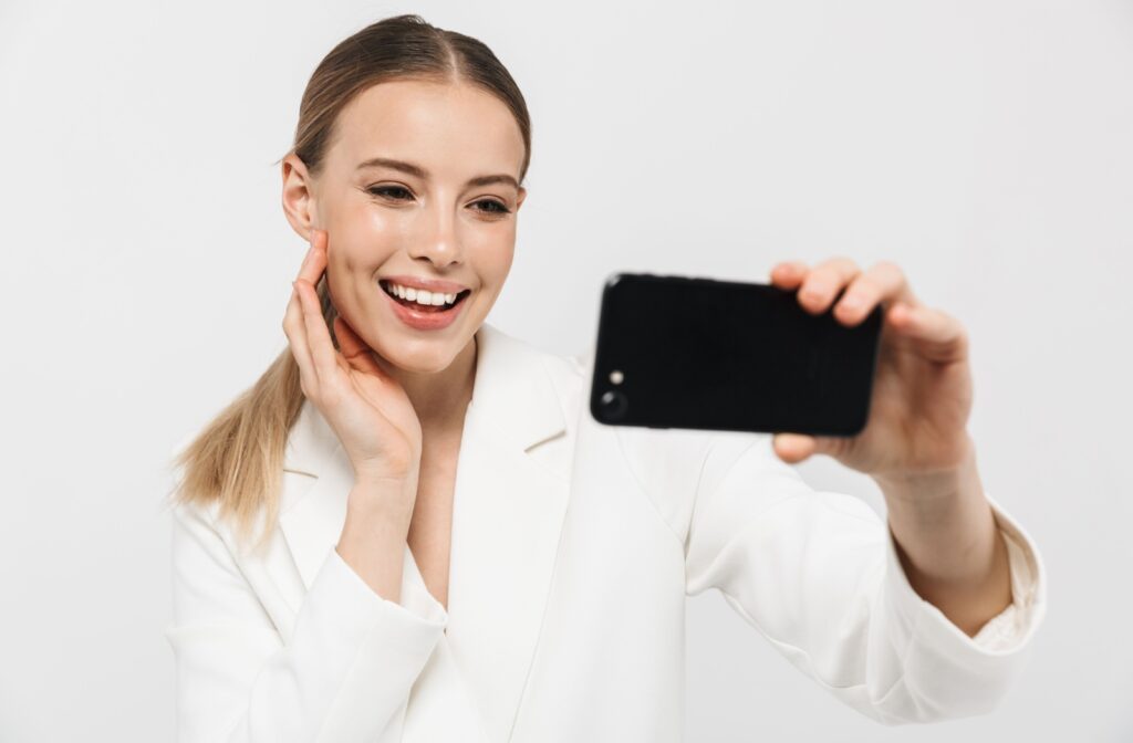 A woman taking a picture of her smile to use for the Invisalign virtual app.