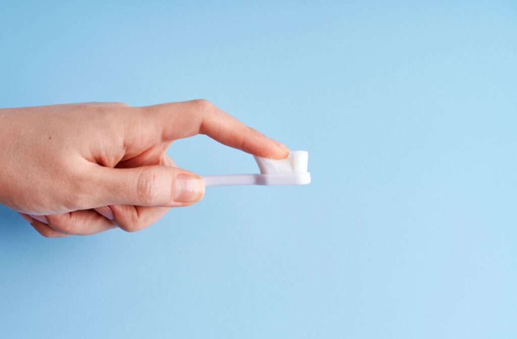 A finger running through the bristles of a soft bristle toothbrush.