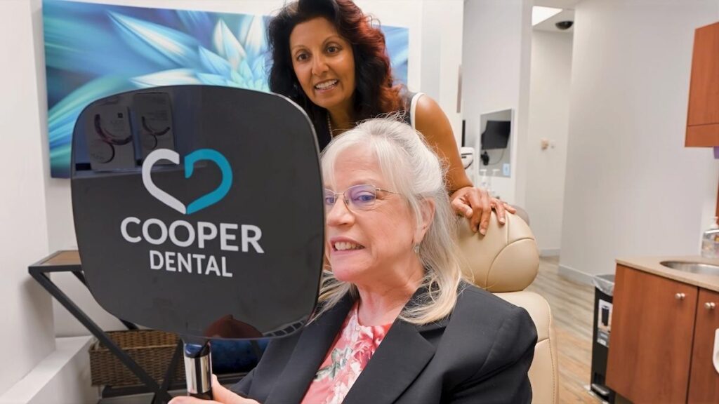 A patient looking at their teeth in a handheld mirror after a dental recall exam from Cooper Dental in downtown Calgary.